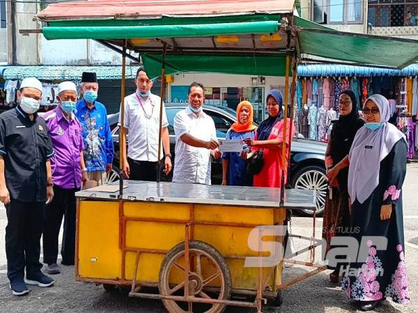 Kak Pah (empat dari kanan) menerima sumbangan kereta sorong baharu yang disampaikan oleh Zulkepli (tengah).