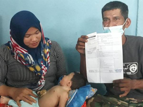 Norliza (kiri) memangku Muhammad Ammar, manakala Sanudin menunjukkan surat rawatan anaknya ketika ditemui di rumah mereka di Kampung Perik, Kuala Nerang hari ini.