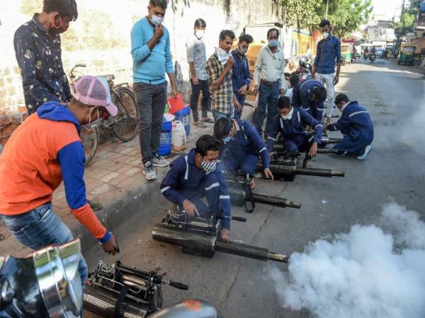 Sekumpulan pekerja menguji alat semburan 'fogging' untuk menghapuskan nyamuk dan virus seperti Covid-19 di Ahmedabad, India. - Foto AFP