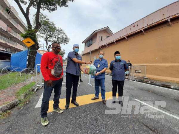 Mohd Afifi (dua dari kiri) menyerahkan bantuan kepada Mohamed Jusoh (dua dari kanan) di hadapan Penjara Pulau Pinang di Georgetown hari ini.