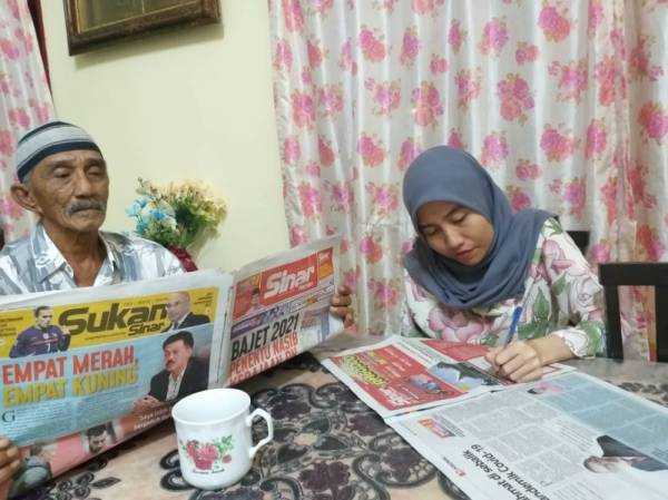 Radin Mohktar (kiri) bersama anaknya, Radin Mariah mengisi borang peraduan Sinar Harian Di Hatiku di rumah mereka di Kampung Parit Bilal, Batu Pahat baru-baru ini.