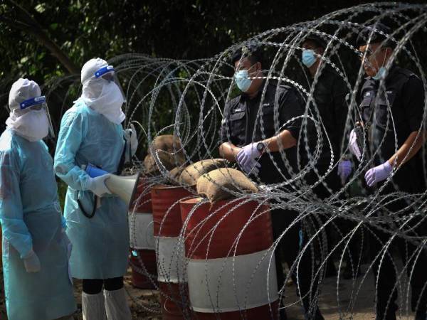 Para petugas kesihatan berbual dengan anggota PDRM yang ditugaskan bagi memantau pergerakan penduduk di semua lorong dan jalan 'tikus' berikutan pelaksanaan PKPD di lokaliti Kluster Saguking pada hari kelapan hari ini. - Foto Bernama