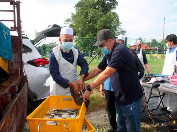 Syed Abu Hussin Hafiz (kiri) memilih ikan kembung untuk diedarkan secara percuma kepada para penduduk pada program Kedai Bergerak Parlimen Bukit Gantang di Taman Mewah, Kamunting hari ini. - Foto Bernama
