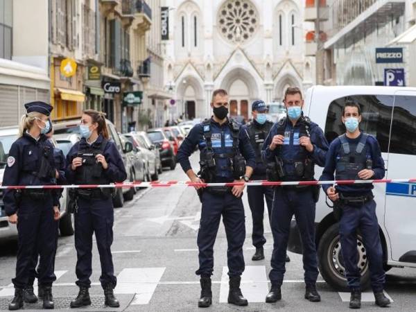 Beberapa anggota polis mengawal laluan ke sebuah gereja yang menjadi lokasi seorang warga Tunisia membunuh tiga orang di Nice semalam. - Foto AFP