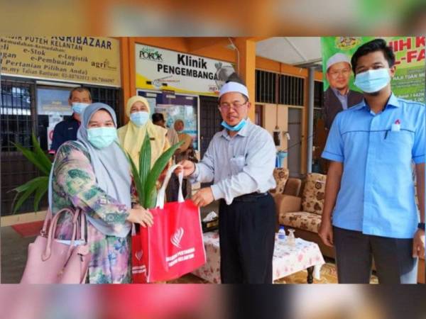 Tuan Mohd Saripudin (dua,kanan) menyampaikan anak pokok kelapa kepada peserta di Parlimen Pasir Puteh.