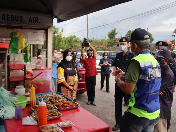 Peniaga mendengar nasihat yang diberikan PDRM pada program Pematuhan dan Pemeriksaan SOP di Taman Rekreasi Sultan Abdul Aziz hari ini.