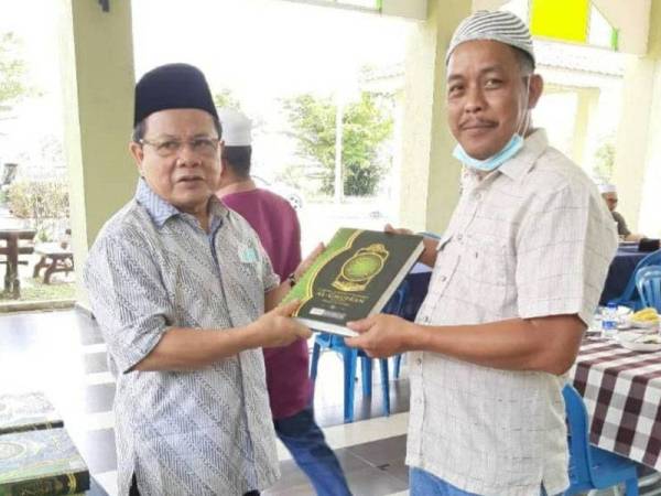 Ahmad (kiri) menyampaikan sumbangan dan al-Quran terjemahan kepada salah seorang pengerusi masjid di Masjid Al-Muttaqin Tedong, Jasin hari ini.