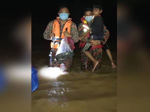 Anggota bomba memindahkan penduduk selepas rumah mereka di Kampung Batu 10, Skudai, Johor Bahru dilanda banjir semalam.