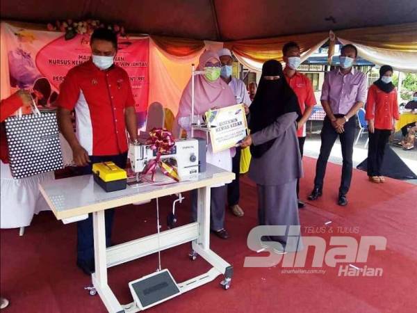 Siti Ashah (dua dari kiri) menyerahkan sijil penghargaan kepada sukarelawan Kemas, agensi kerajaan dan NGO terlibat yang menjayakan projek murni itu sambil disaksikan Noor Azman (kiri) di bengkel jahitan Kemas, Kampung Hujung Bandar.