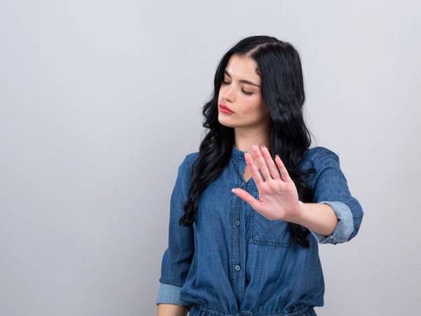 Young woman making a rejection pose on a gray background