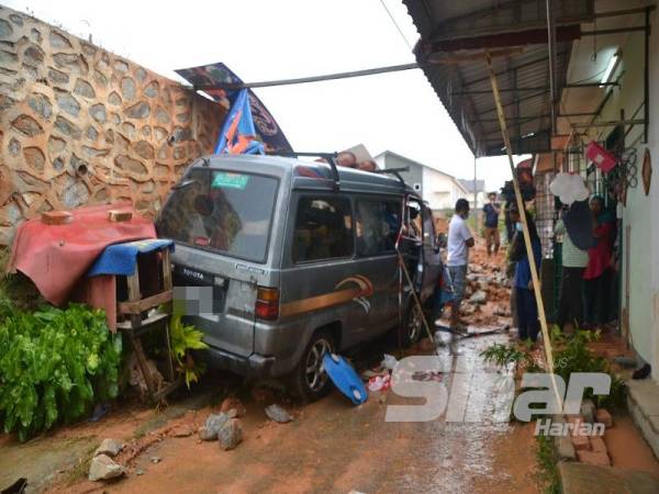 Van yang digunakan Sukri untuk menjual pakaian ditimpa batu dan tanah dari tembok yang runtuh di Taman Bidara Jaya I, Masjid Tanah, Alor Gajah awal pagi tadi