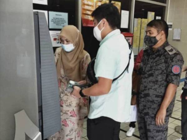 Chuah Chen Ye, sedang melakukan urusan bayaran denda di mesin pembayaran di pekarangan Kompleks Mahkamah Kuala Terengganu hari ini dengan dibantu kakitangan mahkamah bertugas.