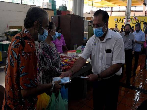 Pengerusi Jawatankuasa Perumahan, Kerajaan Tempatan, Perancangan Bandar dan Desa negeri Pulau Pinang Jagdeep Singh Deo (tiga, kanan) mengedarkan pelitup muka kepada pengunjung Pasar Awam Taman Tun Sardon semasa membuat pantauan prosedur operasi standard (SOP) COVID-19 hari ini.- Foto Bernama