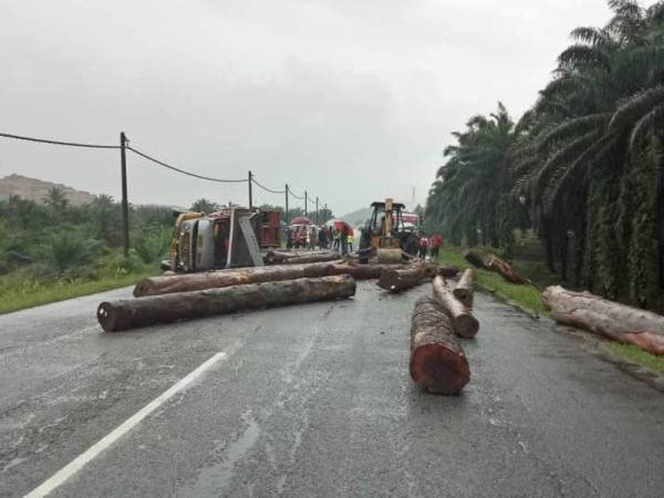 Kayu balak yang bertaburan di tengah jalan raya selepas lori dipandu Nasip Supiadi hilang kawalan sebelum terbalik. -Foto: Ihsan IPD Dungun