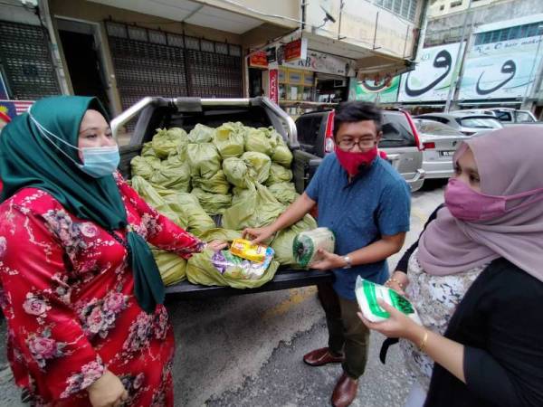 Rozainee (kiri) bersama Shahnun Hanif Abdullah (tengah) melihat antara barangan yang diberikan kepada pengamal media Kelantan hari ini.