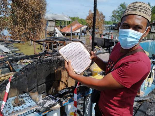 Rosmaini menunjukkan naskah Al- Quran yang masih dalam keadaan baik selepas rumahnya di Kampung Sri Dungun di sini hangus dijilat api dalam kejadian Isnin lalu.