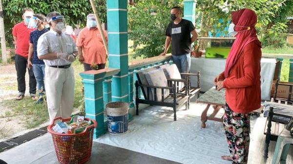 Menteri Kesihatan Datuk Seri Dr Adham Baba (tiga dari kiri) menyerahkan bakul makanan kepada penduduk Kampung Lukut hari ini. -Foto Bernama