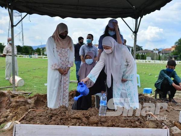 Noor Fuzana (kanan) menyiram pusara suaminya di Tanah Perkuburan Islam Raudhatul Sakinah KL Karak (Taman Selasih), Batu Caves hari ini. Foto: Sinar Harian ASRIL ASWANDI SHUKOR