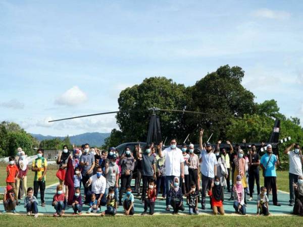 Sebahagian daripada penduduk sekitar pulau ini yang terpilih menaiki helikopter Robinson R44 secara percuma bergambar di hadapan helikopter tersebut di Heli Outpost di sini hari ini. - Foto Bernama