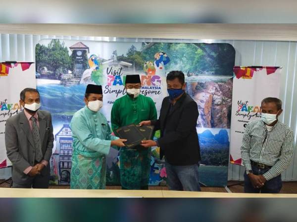 Mohd Sharkar (tengah) menyaksikan upacara bertukar dokumen perjanjian antara Ishak (dua dari kiri) yang mewakili Tourism Pahang dan Azmi Razil pada Majlis Menandatangani MoU antara kedua pihak di Wisma Sri Pahang, Kuantan hari ini.