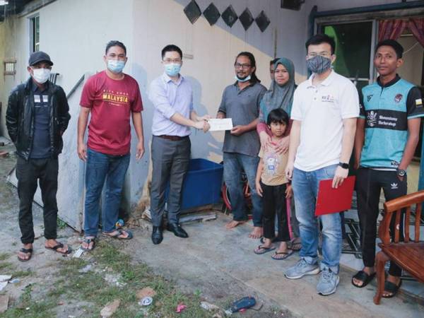 Kah Woh (empat dari kiri) menghulurkan sumbangan kepada mangsa banjir di dalam kawasan DUN Tebing Tinggi, semalam.