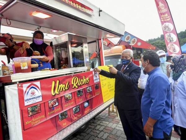 Annuar (tengah) melihat perniagaan food truck Umi Richs yang diusahakan oleh Noor Shareena Adnan (dua dari kiri) dan Dian sempena majlis penyerahan lesen perniagaan kepada Usahawan Muda Kota Wilayah Persekutuan Putrajaya di Dataran Niaga Belia, Tapak Food Truck, Presint 14, Putrajaya hari ini. - Foto Bernama
