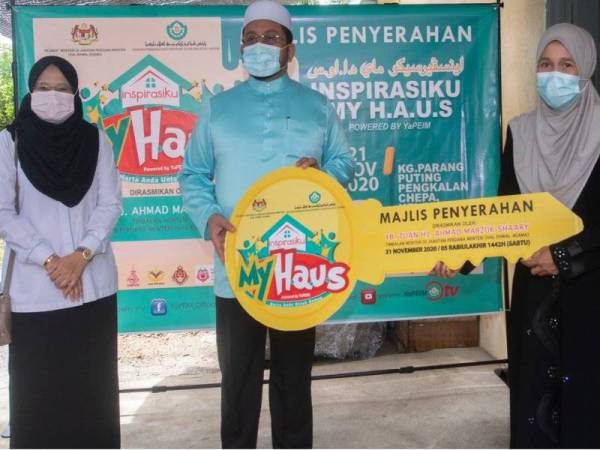 Ahmad Marzuk (tengah) menyerahkan replika kunci kepada Rashidah Semail, 48, (kanan) salah seorang penerima bantuan Program Inspirasiku MyHaus sempena Majlis Penyerahan Program Inspirasiku MyHaus Di Bawah YaPEIM dan Sumbangan Program Foodbank Yayasan Pembangunan Ekonomi Islam Malaysia (YaPEIM) 2.0 Peringkat Negeri Kelantan di Kampung Parang Putting, Batu 6 Pengkalan Chepa hari ini. - Foto Bernama 