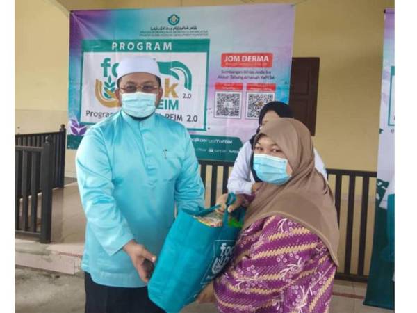 Marzuk (kiri) menyampaikan barangan keperluan di Program Inspirasiku MyHaus dan FoodBank di bawah Yayasan Pembangunan Ekonomi Islam Malaysia (YaPEIM) di Kampung Parang Puting, di sini hari ini.