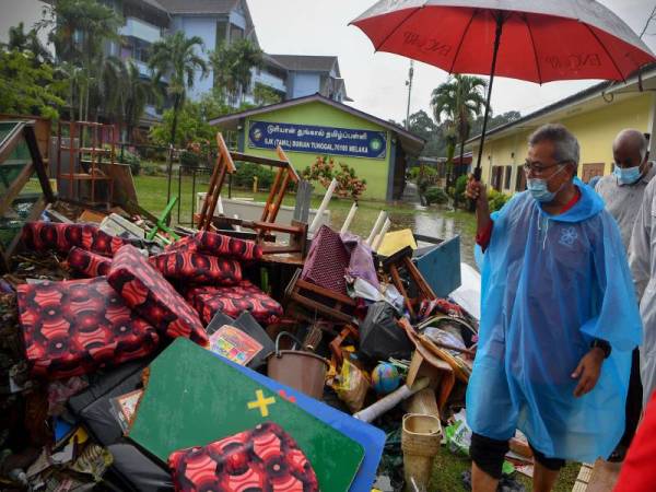 Mohd Redzuan (kiri) melihat kerosakan harta benda akibat banjir semasa mengadakan lawatan ke Sekolah Kebangsaan Jenis Tamil Durian Tunggal hari ini. -Foto Bernama