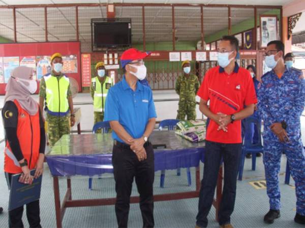 Dr Noor Azmi (dua, kiri) bertanyakan sesuatu kepada petugas mengenai operasi Pusat Penempatan Sementara (PPS) mangsa banjir di Sekolah Kebangsaan Parit Haji Aman, hari ini. -Foto Bernama