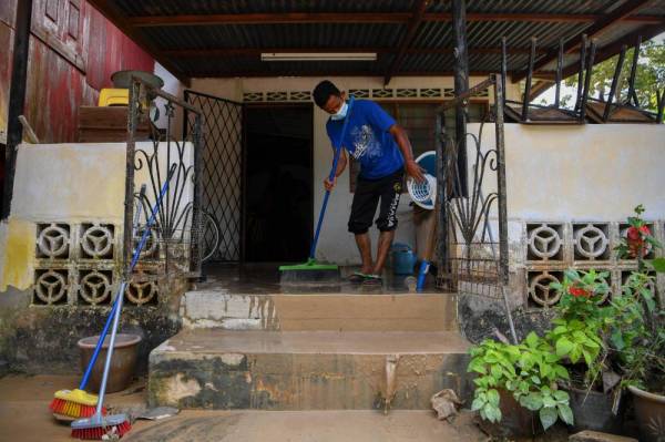 Sukarelawan setempat bergotong royong membersihkan sebuah rumah penduduk warga emas yang terjejas susulan banjir kilat ketika tinjauan di Kampung Gadek Dalam, Melaka. -Foto Bernama