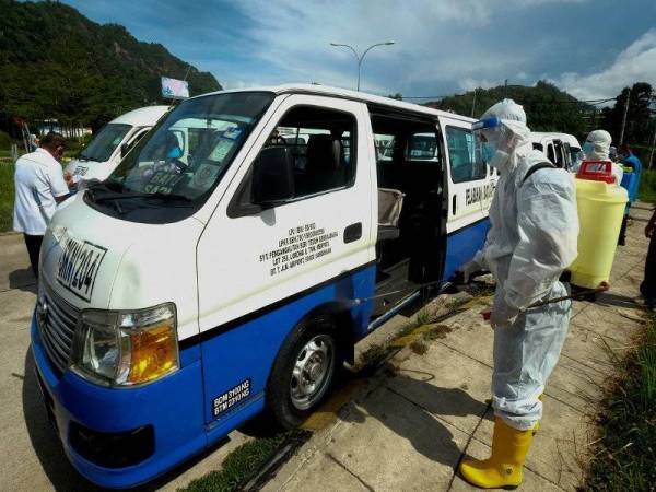 Anggota Bomba dan Penyelamat melakukan sanitasi pada van henti-henti laluan Batu Sapi hari ini. Foto Bernama