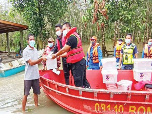 Azmir (kanan) dan Muhammad Fareez (dua dari kanan) serta pasukan penyelamat menyampaikan bantuan makanan kepada penduduk di Kampung Tasek, Pak Kundor, Pasir Puteh yang terperangkap akibat banjir semalam.