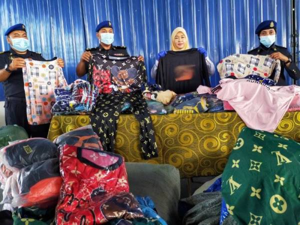 Norazah (dua dari kanan) menunjukkan baju tidur tiruan pelbagai jenama yang dirampas di sebuah premis di Perlis semalam.