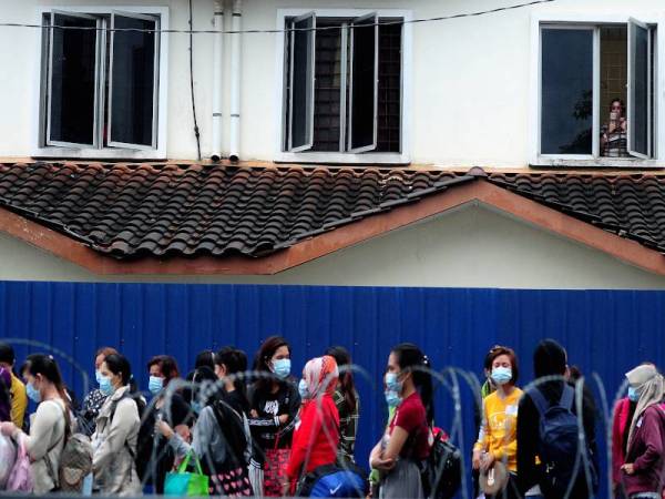 Sebahagian pekerja wanita Top Glove yang beratur sebelum dibawa keluar oleh petugas kesihatan berikutan penularan wabak Covid-19 di Asrama Pekerja Top Glove Meru Klang baru-baru ini. - Foto Bernama