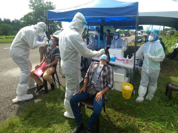 Petugas Pejabat Kesihatan Sandakan mengambil sampel dari hidung para pengguna jalan raya sewaktu mengadakan saringan COVID-19 di sekatan jalan raya di Jalan Lintas, Sibuga hari ini. - Foto Bernama