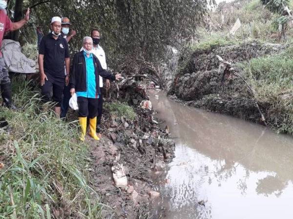 Hassan menunjukkan lokasi tebing sungai yang runtuh hingga mengakibatkan aliran air sempat lalu banjir di Kampung Sungai Rinting D, Pasir Gudang hari ini.