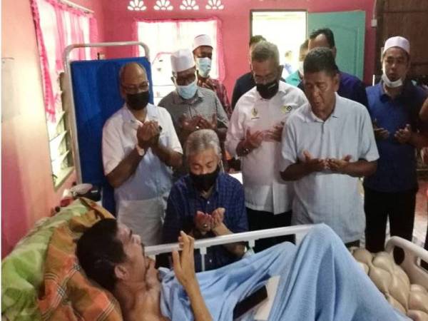 Ahmad Zahid (duduk) membacakan doa ketika menziarahi Muhamad Zan Mat Zain, 33, ketika Program Ziarah Kasih di Kampung Rungkup Kecil hari ini.