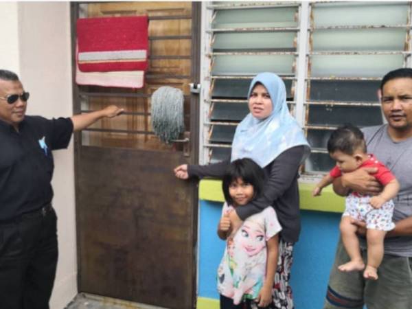 Siti Noraini bersama suaminya (kanan) menunjukkan pintu dapur rumahnya diketuk semasa lawatan Zulkifli (kiri) ke rumahnya hari ini.