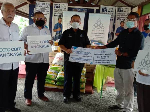 Abdul Fattah (tengah) menyerahkan sumbangan kepada wakil Koperasi Keluarga Haji Sulaiman, Datuk Hanafi Sulaiman menerusi program CSR Coopcare di Bilik Gerakan Kampung Kuala Sawah, Rantau hari ini.