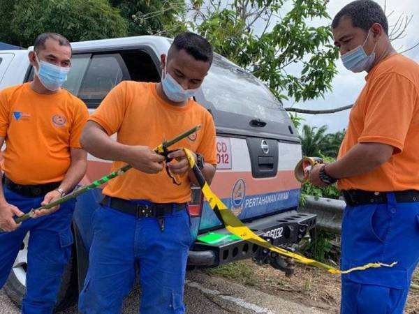 Nazizul (kanan) membantu anggota APM yang lain menyediakan batang buluh untuk diletakkan di beberapa kawasan yang ditenggelami air di Tumpat semalam.