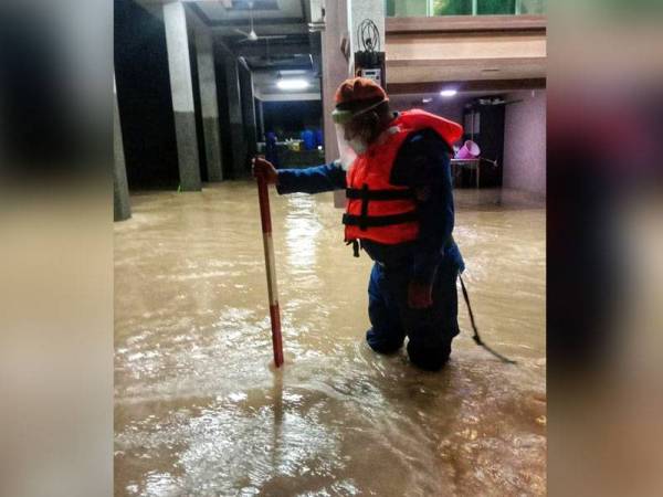 Seorang anggota APM Kulim sedang memeriksa paras air di sebuah kawasan yang terlibat dengan banjir. -Foto ihsan APM