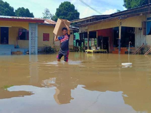 Musaidi muhammad,24, mengangkat barang untuk dipindahkan ke tempat tinggi selepas rumahnya di Kampung Lubok Gong mula dilimpahi air Sungai Golok.