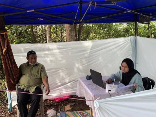 Nurlieda Khaleeda ditemai ayahnya mengikuti kelas dalam talian di khemah dibina di Bukit Petai Tujuh di Tanah Merah hari ini.