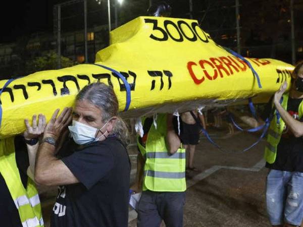 Beberapa penunjuk perasaan mengusung sebuah replika kapal selam ketika tunjuk perasaan menentang skandal rasuah dalam pembelian peralatan tentera itu di Tel Aviv baru-baru ini. - Foto AFP