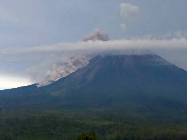 Gunung berapi Semeru memuntahkan debu panas sejauh 3,000 meter di lereng bukit hingga mencetuskan panik kepada penduduk kampung sekitar awal pagi tadi. - Foto AFP