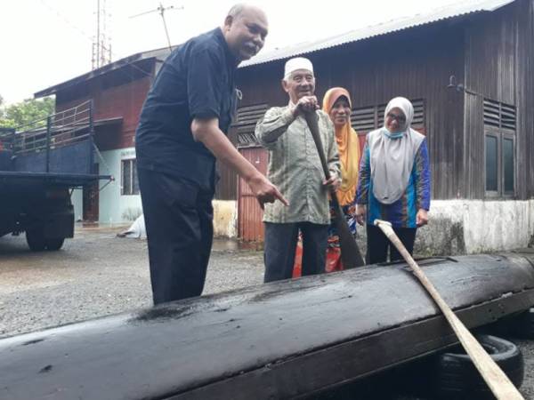 Dari kiri: Mohd Kasri dan Mat Isa melihat keadaan perahu sagor di Kampung Chegar sebelum dipindahkan ke dalam lori untuk dibawa ke Universiti Utara Malaysia (UUM) semalam.