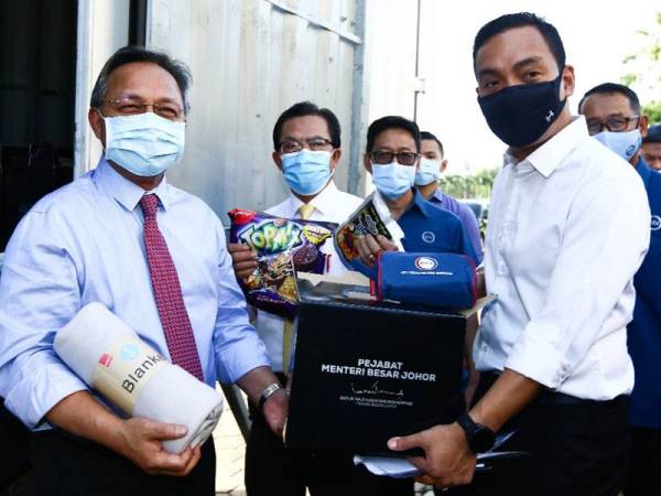 Hasni (kiri) menunjukkan bakul makanan yang dihantar kerajaan negeri Johor ke Singapura hari ini.