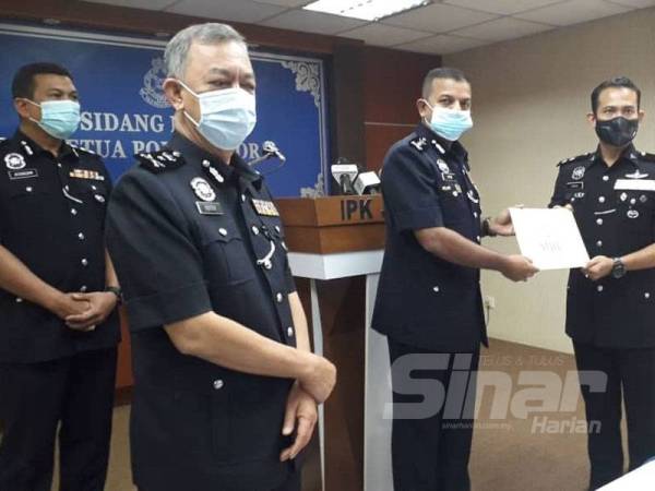 Ayob Khan (tengah) menyerahkan sijil penghargaan daripada Ketua Polis Negara kepada anggota polis yang melakukan operasi di pusat hiburan dan menolak rasuah selepas sidang media di IPK Johor, Johor Bahru, hari ini.