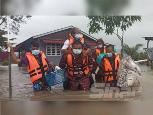 Pasukan bomba dan penyelamat membantu penduduk Kampung Padang Kemunting, Kuala Nerus berpindah ke pusat pemindahan sementara selepas rumah mereka dinaiki air hari ini.